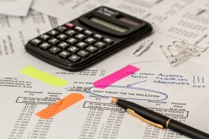 Image is some tax paperwork with a calculator on top.