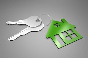 Image is a house shaped key ring with two keys attached to it.